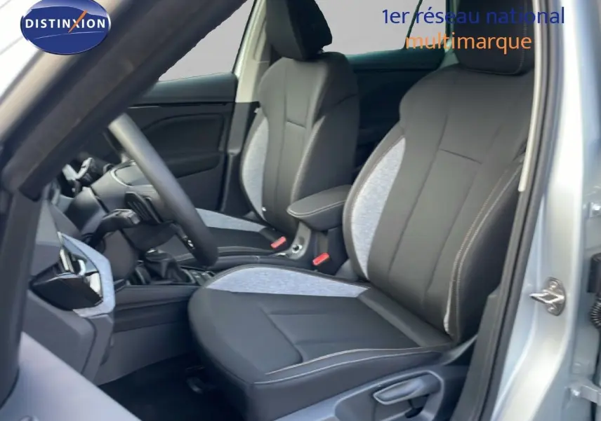 Vue intérieure côté conducteur du Skoda Kamiq gris argent, mettant en valeur les sièges avant bi-matière noir et gris clair.