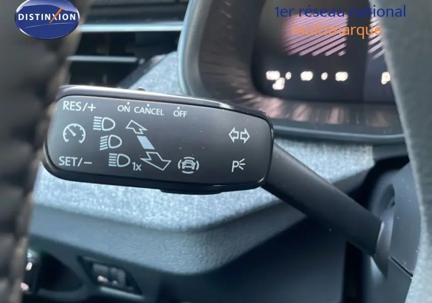 Gros plan sur la commande de régulateur de vitesse à gauche du volant dans un Skoda Kamiq gris argent métal.