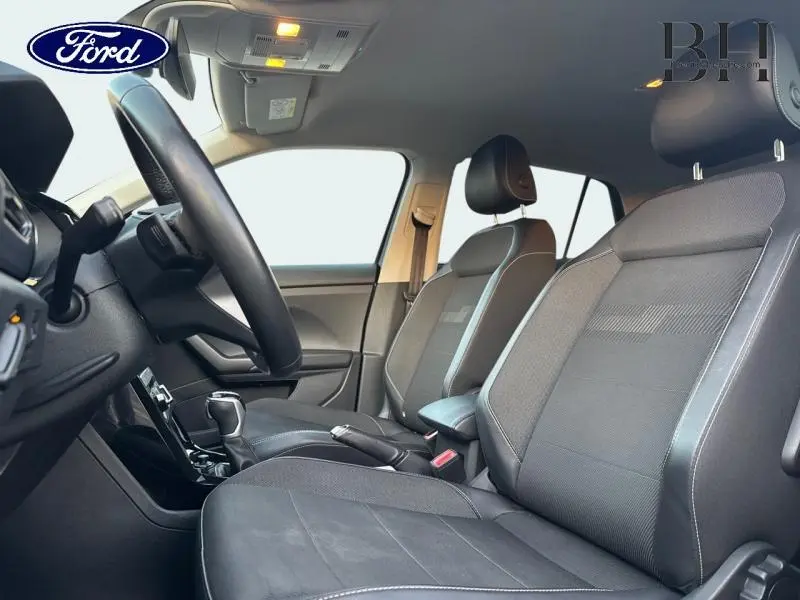 Vue intérieure côté conducteur du Volkswagen T-Cross 2022, sièges noirs avec volant cuir multifonction.