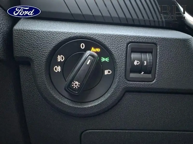 Commande des phares et réglage de l’éclairage intérieur sur tableau de bord noir, vue rapprochée côté conducteur.