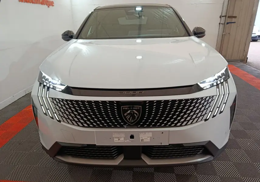 Vue avant d’un Peugeot 3008 blanc 2025 avec calandre noire distinctive et phares LED allumés.
