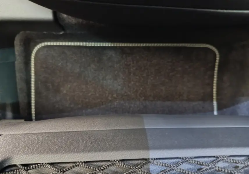 Détail du tapis de sol noir avec surpiqûres blanches dans un Peugeot 3008 blanc, vue intérieure côté passager.