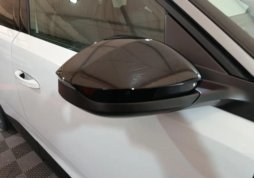 Gros plan sur le rétroviseur noir côté conducteur d’un Peugeot 3008 blanc, vue latérale gauche.