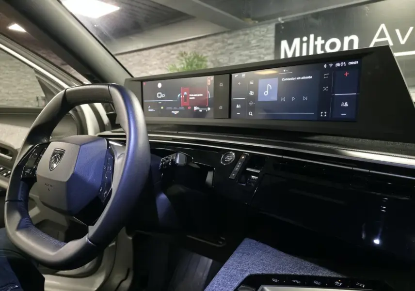 Vue intérieure du tableau de bord du Peugeot 5008 blanc 2025, avec volant compact et double écran HD panoramique.