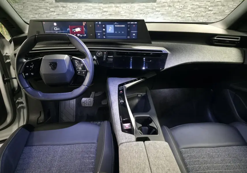 Vue intérieure avant du Peugeot 5008 2025, tableau de bord avec double écran HD et volant compact cuir noir.