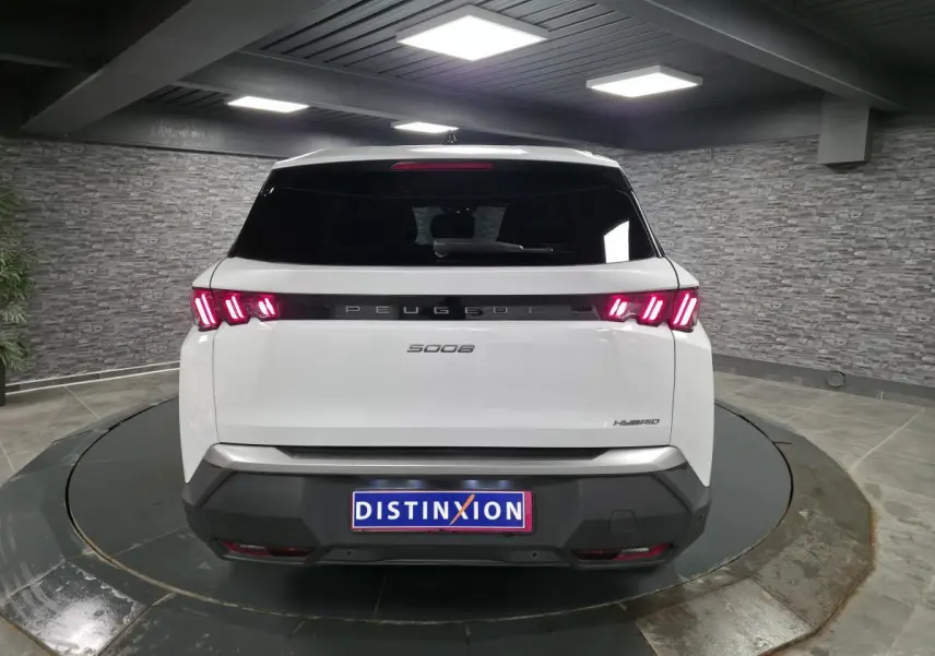 Vue arrière d'un Peugeot 5008 blanc hybride 2025 avec feux arrière LED 3 griffes et bandeau noir laqué.