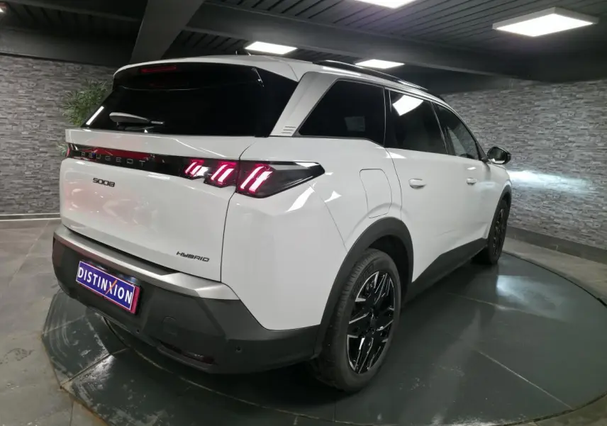 Vue 3/4 arrière droite du Peugeot 5008 hybride blanc avec feux arrière à LED 3 griffes et jantes alliage noires.