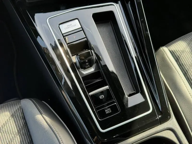 Gros plan sur la console centrale noire brillante de la Volkswagen Golf 1.5 eTSI R-Line 2024 avec sélecteur de boîte auto et boutons Start/Stop.