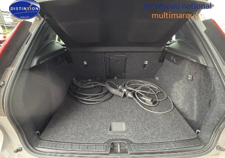 Coffre ouvert vu de l'arrière d'un Volvo XC40 gris 2023 avec câbles de recharge hybride visibles.