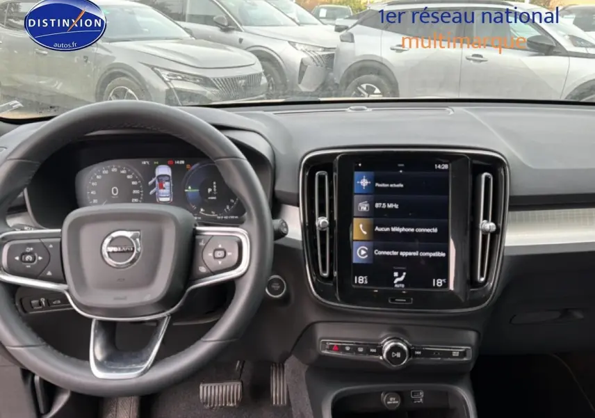 Vue intérieure frontale du tableau de bord du Volvo XC40 gris, avec volant cuir multifonction et écran tactile central.