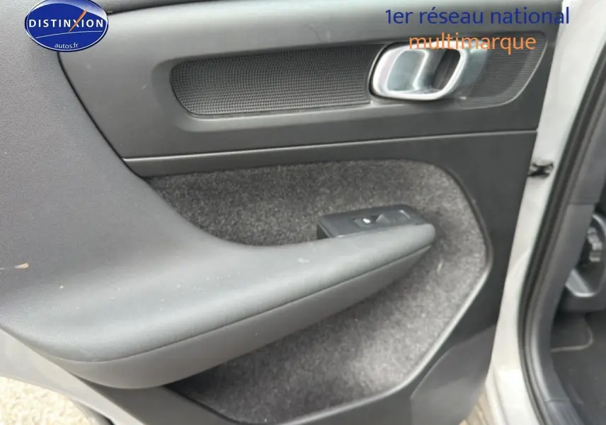 Vue rapprochée de la porte avant droite grise du Volvo XC40 T4 recharge avec accoudoir et commande de vitre.