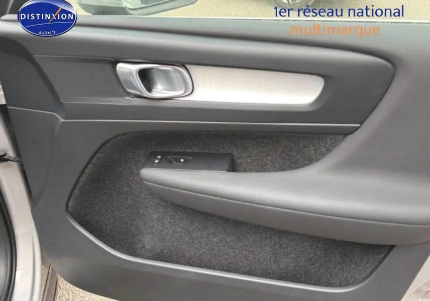 Intérieur côté gauche de la porte avant grise du Volvo XC40 T4 hybride, avec poignée argentée et commande de vitre.