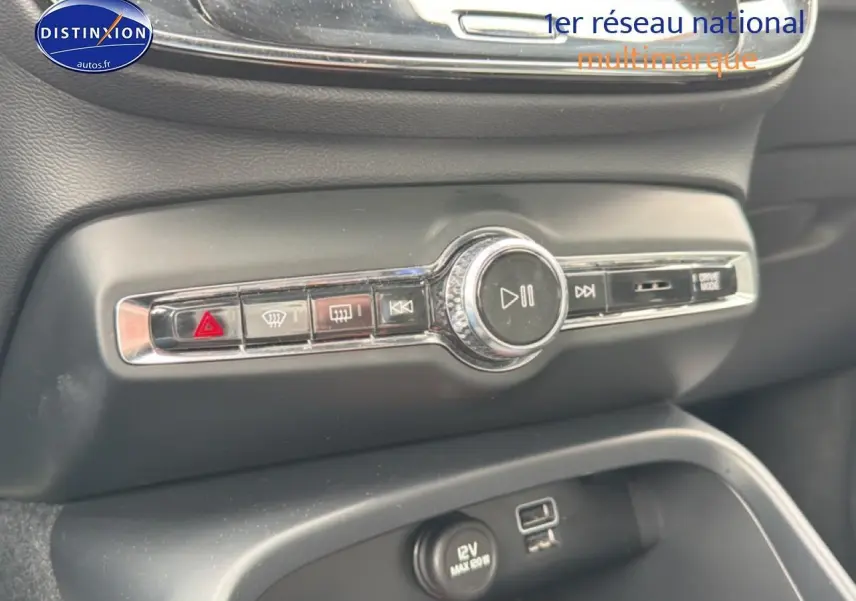 Gros plan sur la console centrale noire du Volvo XC40 T4 recharge 2023, avec commandes audio et prise 12V visible.