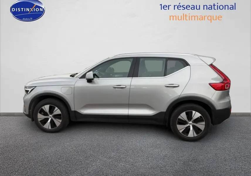 Profil côté gauche d'un Volvo XC40 T4 hybride gris 2023 avec jantes alu et becquet arrière visible.