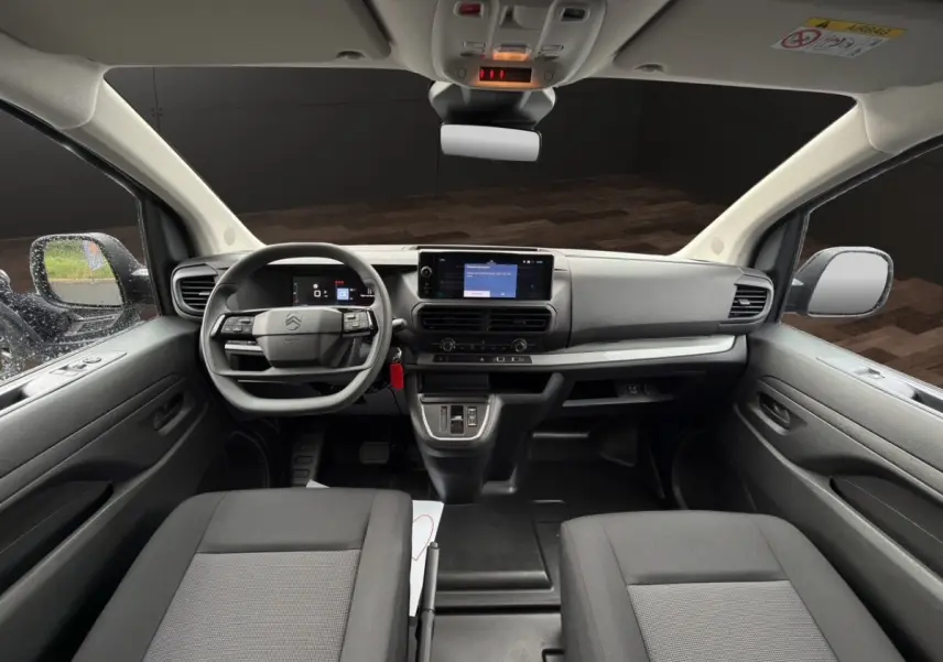 Vue intérieure avant du Citroën Jumpy XL gris foncé, tableau de bord moderne avec écran tactile central et volant multifonctions.