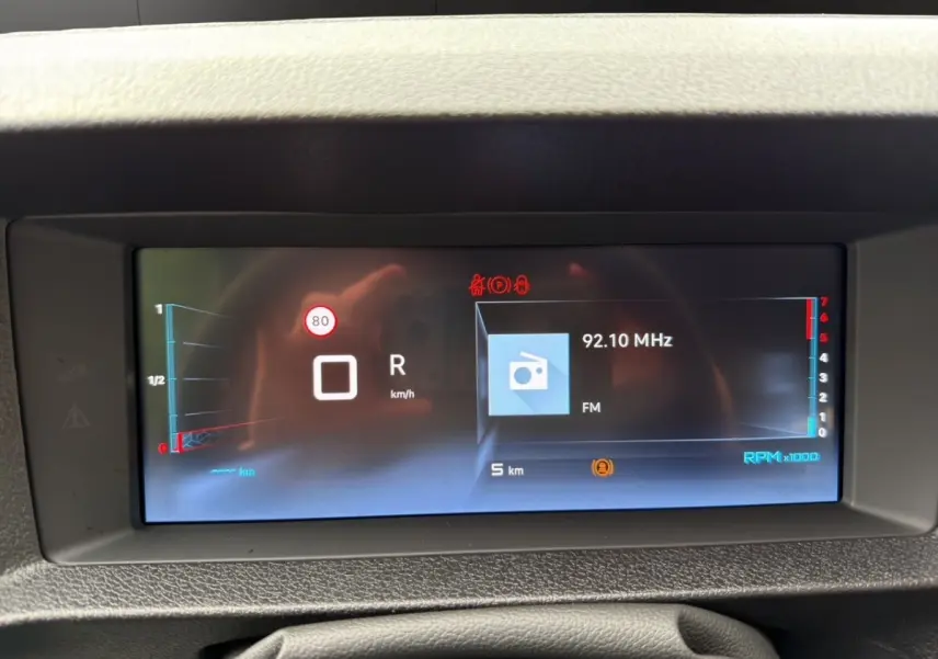 Affichage numérique du tableau de bord du Citroën Jumpy XL gris foncé, montrant la vitesse, la radio FM et le régime moteur.