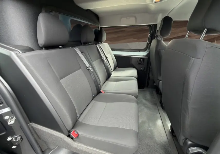 Vue intérieure côté droit sur la banquette arrière grise du Citroën Jumpy XL 2026 avec cloison vitrée et ceintures visibles.