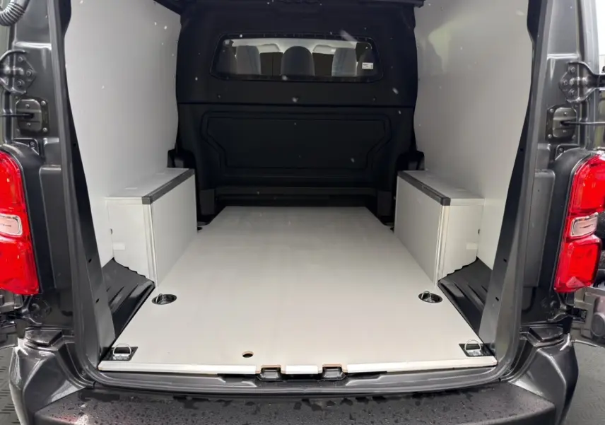 Vue arrière du Citroën Jumpy XL gris foncé, montrant l’espace de chargement avec cloison vitrée et kit bois.