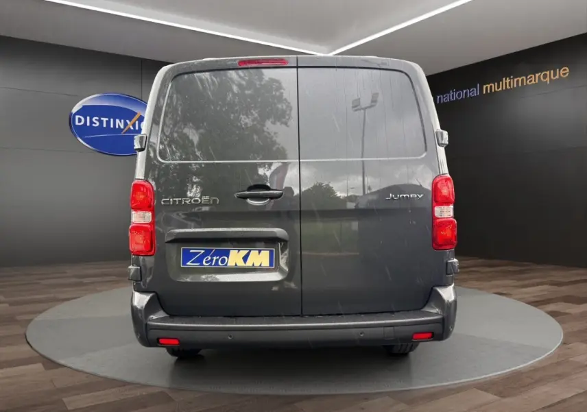 Vue arrière d'un Citroën Jumpy gris foncé avec portes battantes et feux rouges en intérieur showroom.