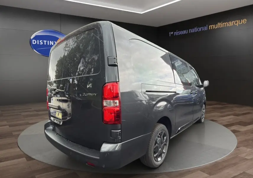Vue 3/4 arrière droit d'un Citroën Jumpy XL gris foncé avec feux arrière rouges et jantes noires.