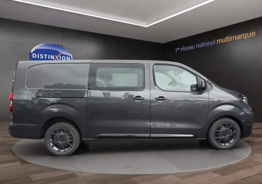 Vue latérale droite d’un Citroën Jumpy XL gris foncé avec vitres avant et porte coulissante en showroom.