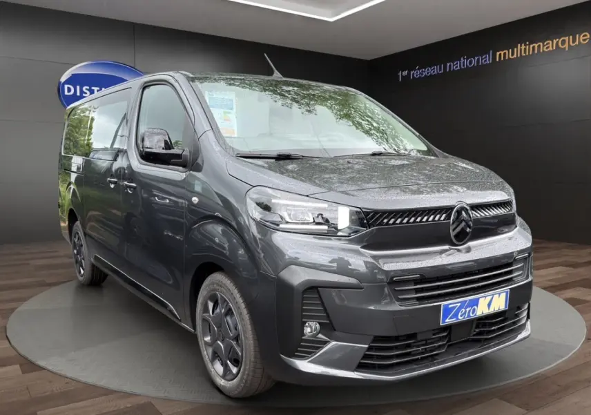 Vue 3/4 avant d'un Citroën Jumpy XL gris foncé avec phares LED et jantes noires en présentation showroom.