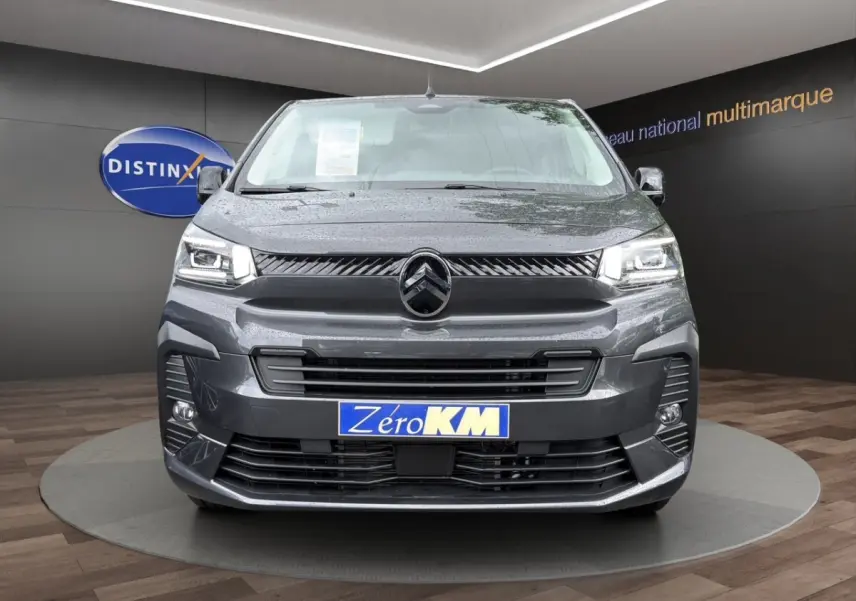 Vue de face d'un Citroën Jumpy XL gris foncé avec phares LED et calandre noire brillante dans un showroom.