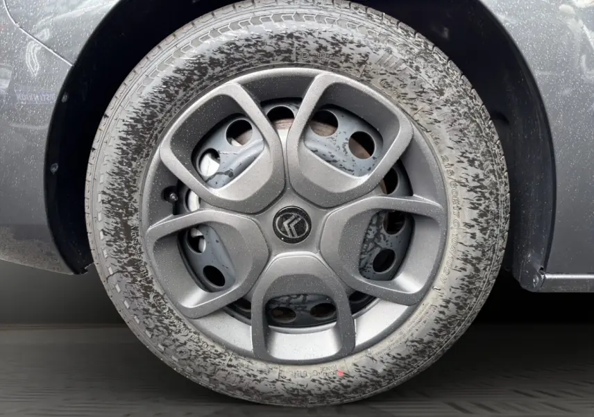 Gros plan sur la roue arrière droite d’un Citroën Jumpy gris foncé avec traces de boue sur le pneu.
