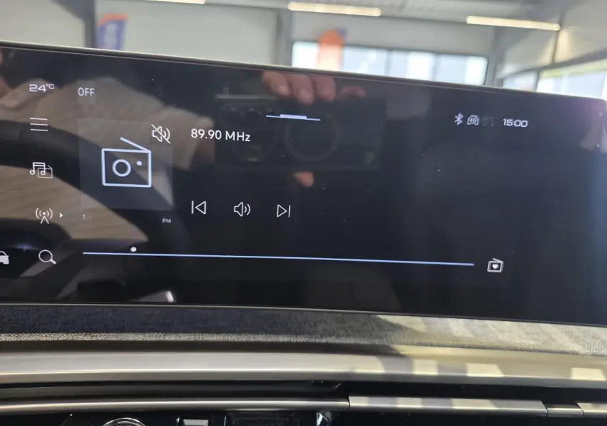 Écran tactile central du Peugeot 3008 Hybrid 2026 affichant la radio FM à 89,90 MHz, avec décor tissu Rimini chiné.