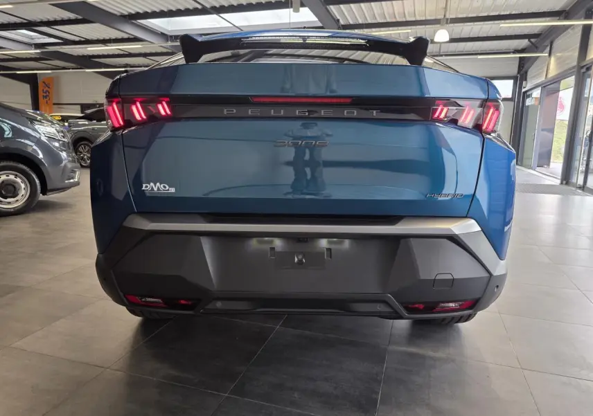 Vue arrière d’un Peugeot 3008 hybride bleu métallisé avec feux arrière LED à trois griffes et bandeau noir laqué.