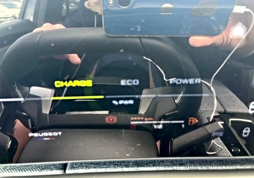 Vue rapprochée du tableau de bord numérique et volant cuir noir du Peugeot 3008 gris titane hybride 2025.