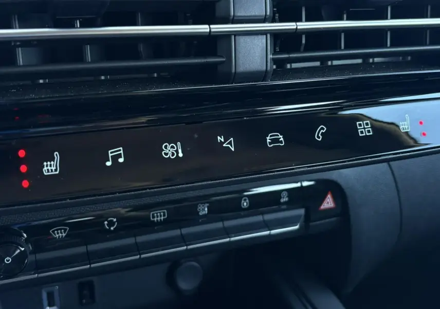 Détail de la console centrale noire brillante du Citroën C5 Aircross Hybrid 2025 avec commandes tactiles et voyants rouges allumés.
