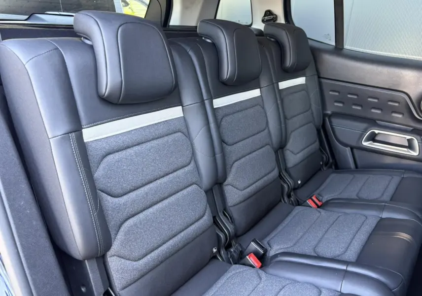 Vue intérieure des trois sièges arrière indépendants en tissu gris et cuir noir du Citroën C5 Aircross Hybrid 2025.