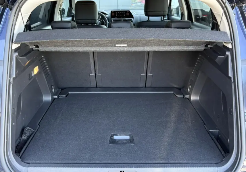 Coffre ouvert vu de l'arrière d'un Citroën C5 Aircross Hybrid bleu Eclipse, avec banquette arrière et tablette cache-bagages visibles.
