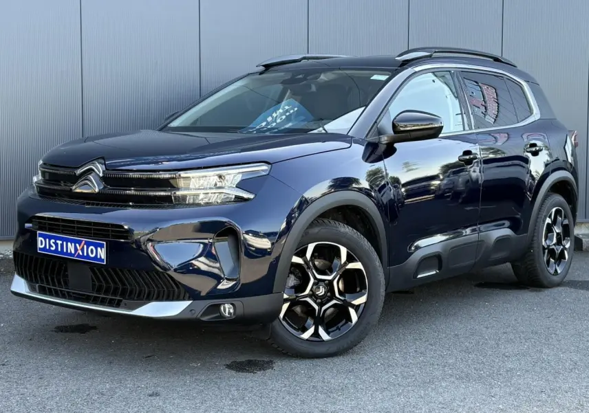 Vue 3/4 avant droite du Citroën C5 Aircross Hybrid 2025 bleu Eclipse avec jantes alliage et barres de toit noires.