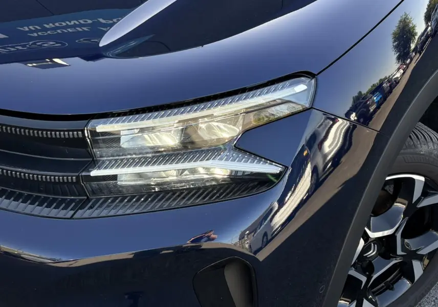 Gros plan sur l'avant droit bleu Eclipse du Citroën C5 Aircross Hybrid avec phares LED et jante alliage bi-ton.