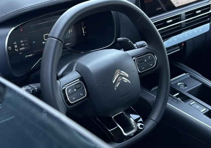 Vue rapprochée du volant noir et du tableau de bord numérique du Citroën C5 Aircross Hybrid 2025.