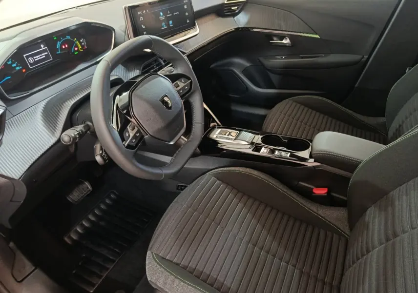 Intérieur de la Peugeot 208 électrique 2024, vue côté conducteur, volant cuir et tableau de bord digital.