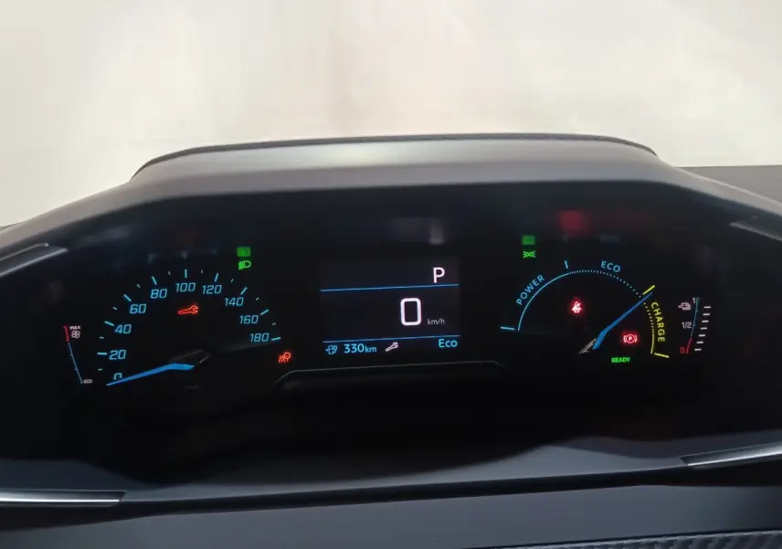 Tableau de bord numérique de Peugeot 208 électrique 2024, affichage vitesse, autonomie et charge batterie en vue frontale.