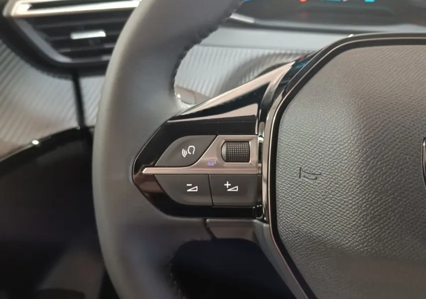 Gros plan sur le côté gauche du volant cuir multifonctions du Peugeot 208 électrique gris clair 2024.