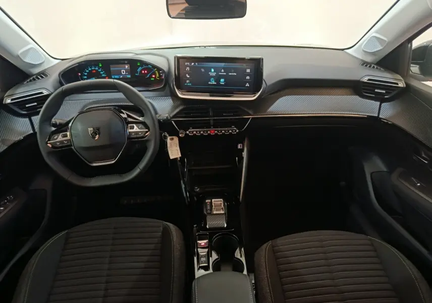 Vue intérieure avant de la Peugeot 208 électrique 2024, tableau de bord moderne avec écran tactile et volant multifonctions cuir.