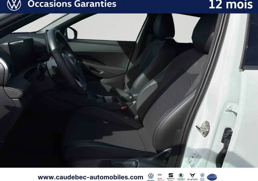 Vue intérieure côté conducteur du Volkswagen T-Roc blanc 2025, montrant les sièges sport et le volant multifonction cuir.