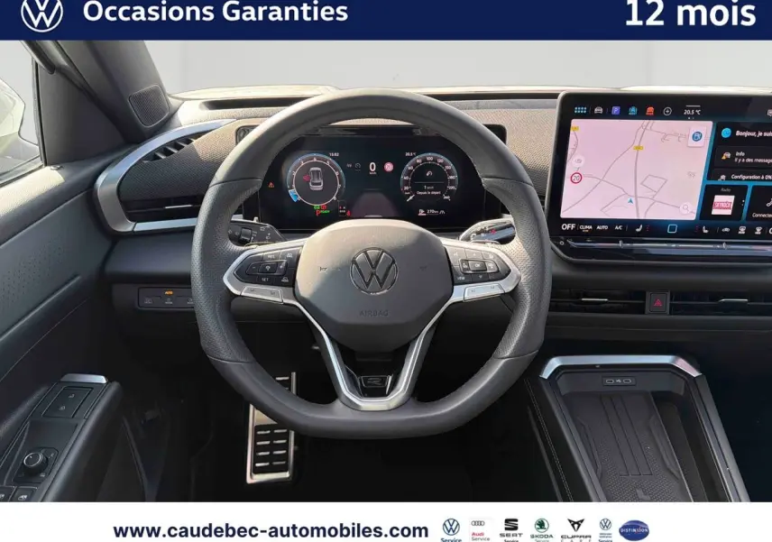 Vue intérieure centrée sur le volant sport cuir du Volkswagen T-Roc blanc avec tableau de bord numérique et écran tactile.