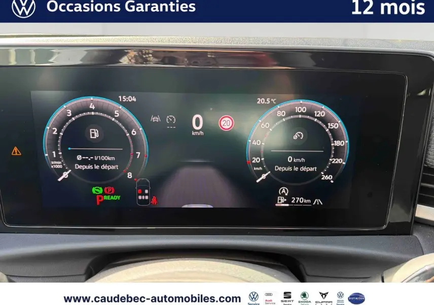 Vue rapprochée du tableau de bord numérique du Volkswagen T-Roc blanc, affichant la vitesse et les indicateurs.