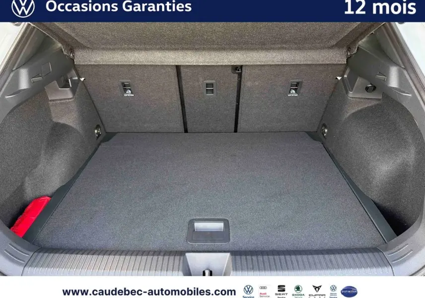 Coffre ouvert du Volkswagen T-Roc blanc, vue de l'arrière montrant un espace de chargement propre et spacieux.