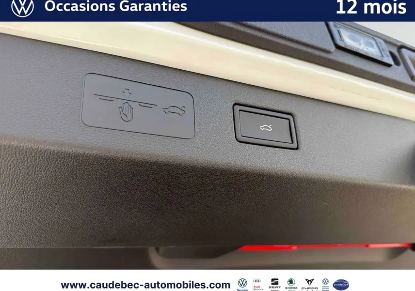 Gros plan sur le bouton d'ouverture électrique du hayon du Volkswagen T-Roc blanc, intérieur du coffre visible.