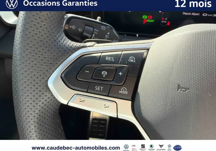 Gros plan sur le volant multifonction cuir noir perforé du Volkswagen T-Roc blanc, avec commandes de régulateur de vitesse.