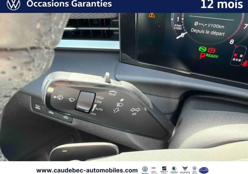 Gros plan sur la commande d’essuie-glace et tableau de bord numérique du Volkswagen T-Roc blanc, intérieur moderne.
