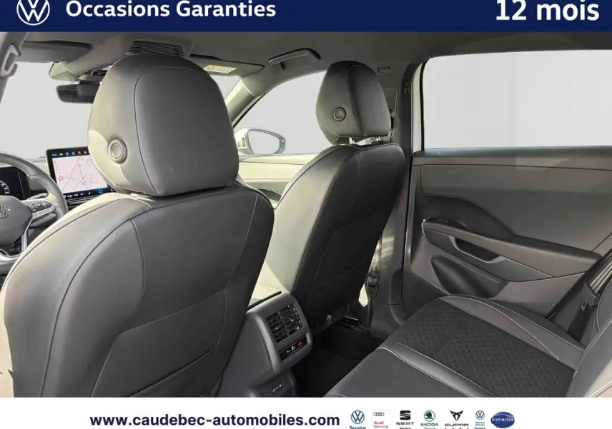 Vue intérieure arrière du Volkswagen T-Roc 2025 avec sièges en cuir noir et console centrale avec aérateurs et commandes climatiques.