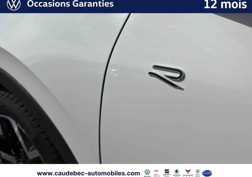 Détail du logo "R" sur la porte côté gauche d'un Volkswagen T-Roc blanc, jante noire visible en arrière-plan.